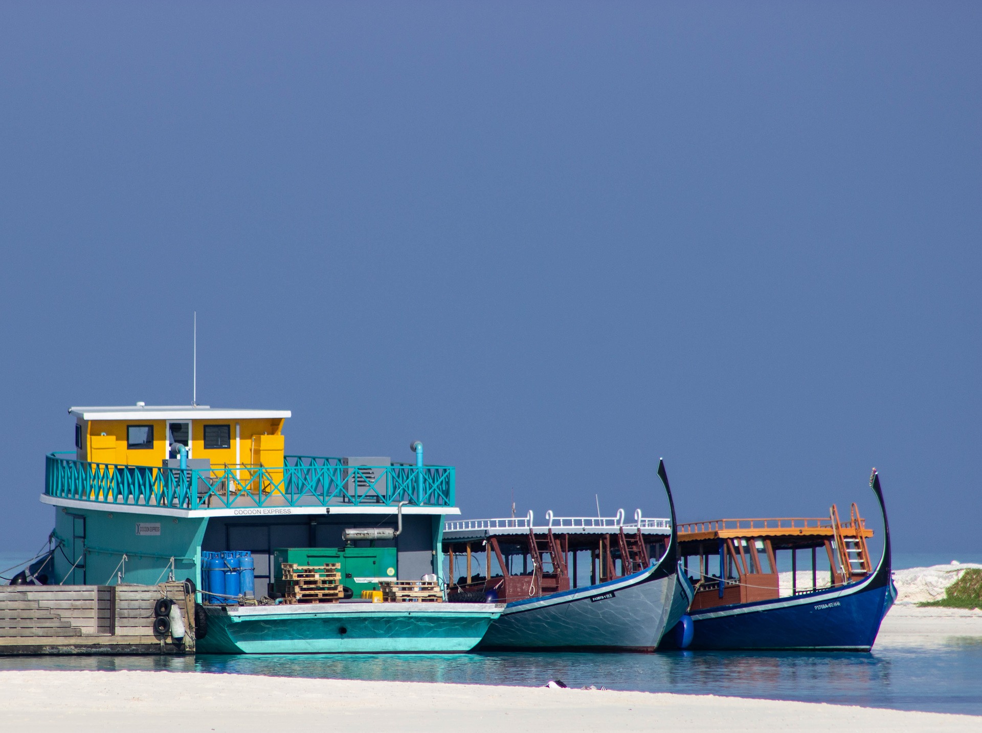 青い空と海に浮かぶ小型フェリーと乗り場の写真